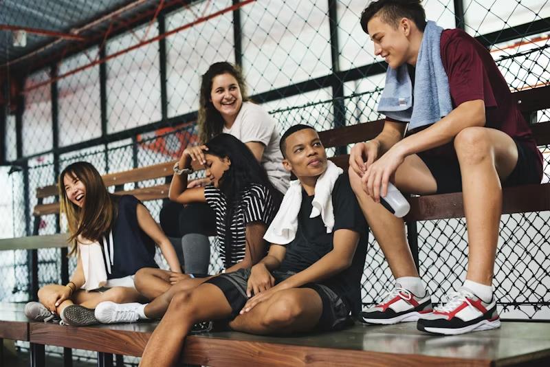 Teenagers sitting together on a bench after school