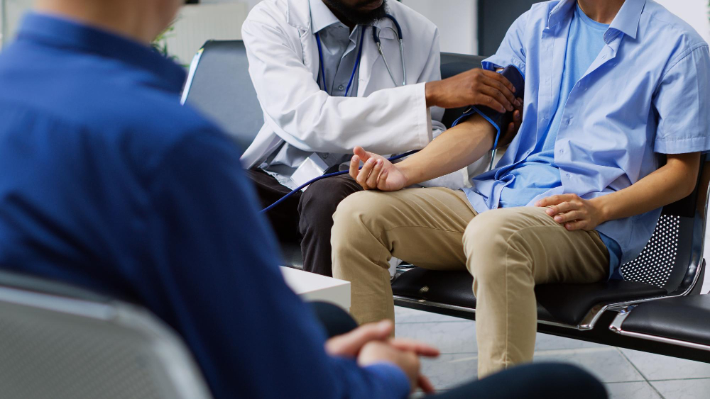 Patient having their blood pressure checked in a busy waiting area