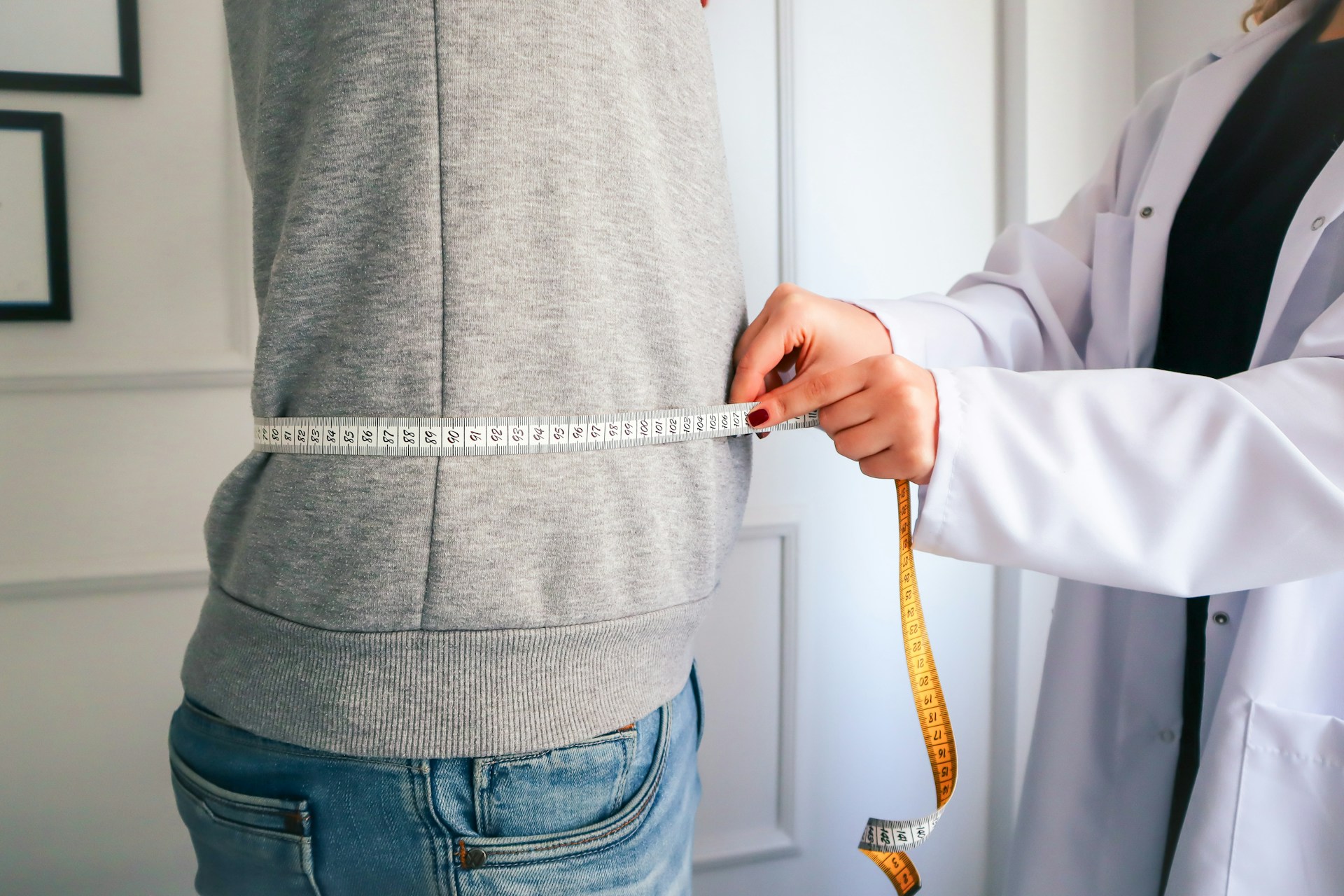 Clinician measuring a patient’s waistline during a weight-loss visit